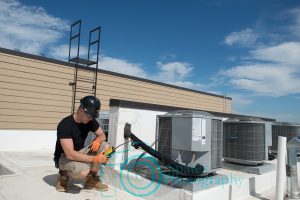 Hvac technician using a refrigerant leak detector on air conditioner refrigerant line