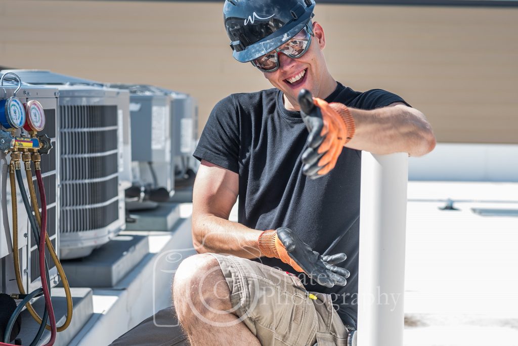 Likeable, happy, hvac technician smiling, wearing safety gear, glasses, hardhat and gloves