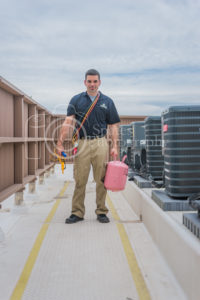 hvac technician with repair tools refrigerant, gauges, meter, standing next to condensing units on roof