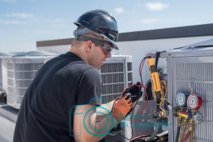 HVAC technician wearing safety gear, working on a air conditioner condensing unit outside