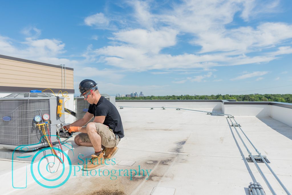 Hvac technician working on an air conditioning unit with lots of open space