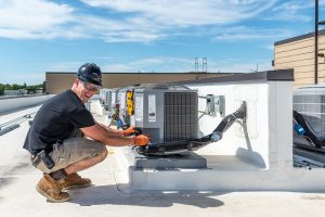 HVAC technician on rooftop next to carrier condensing unit