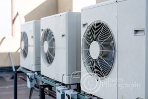 Three ductless mini-split air conditioners on a rooftop of a building